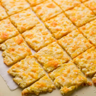 Cozy homemade sourdough crackers with cheddar cheese on a rustic wooden board.