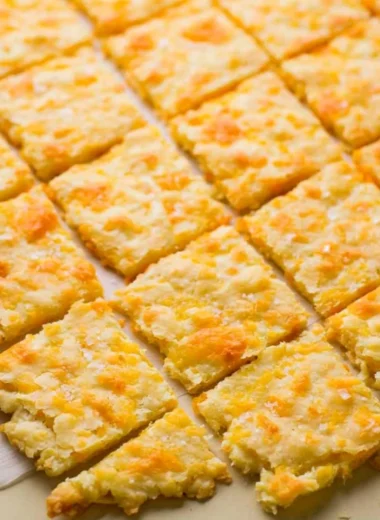 Cozy homemade sourdough crackers with cheddar cheese on a rustic wooden board.