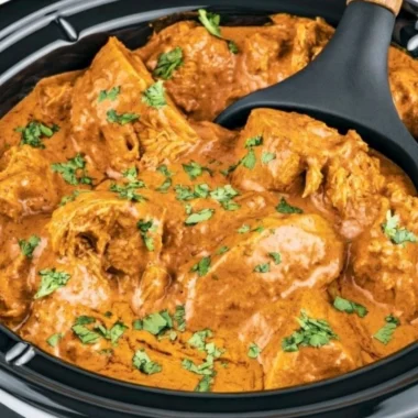 Delicious slow cooker butter chicken served with rice and garnished with cilantro.