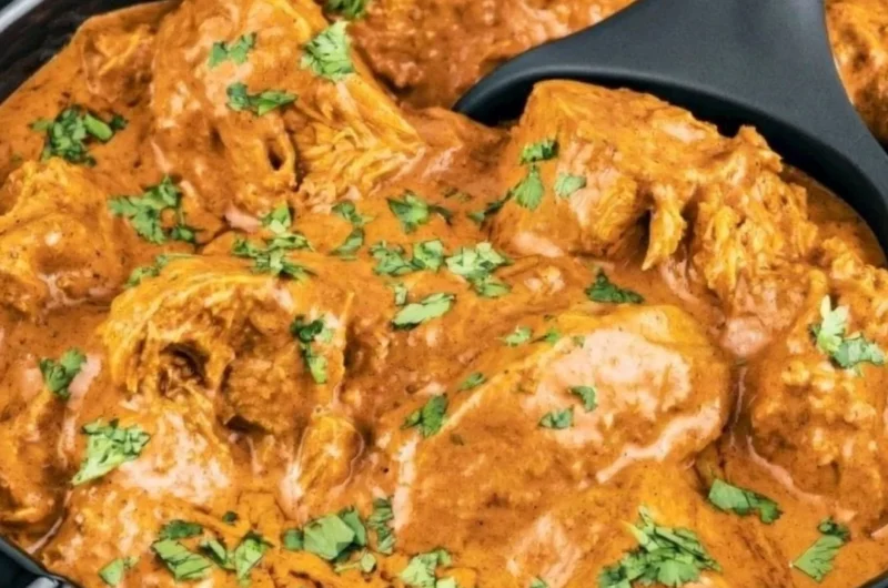 Delicious slow cooker butter chicken served with rice and garnished with cilantro.