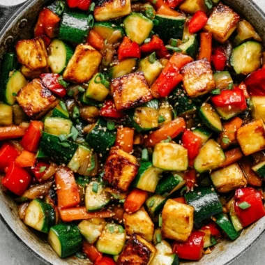 Vibrant zucchini stir fry with tofu, garnished with fresh herbs and spices.